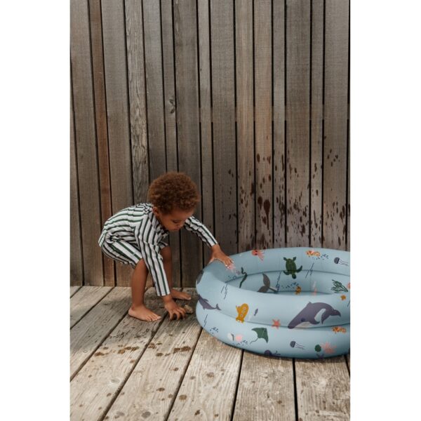 petite garçon qui joue avec sa piscine gonflable aux motifs animaux marins