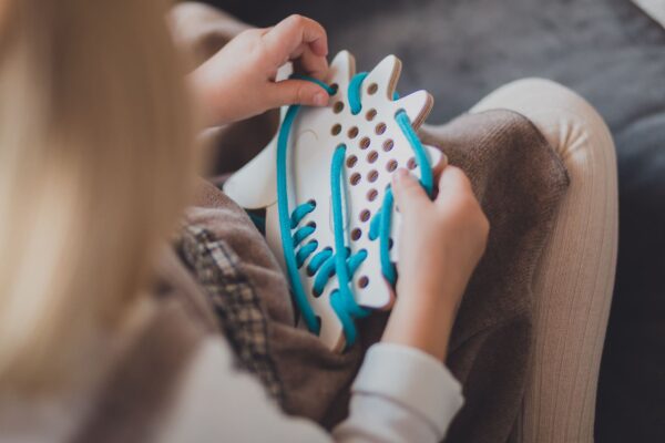 petite fille qui joue avec un jouet à lacer en bois en forme d'hérisson