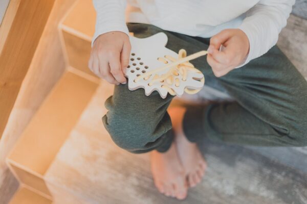 petite fille qui joue avec un jouet à lacer en bois en forme d'hérisson