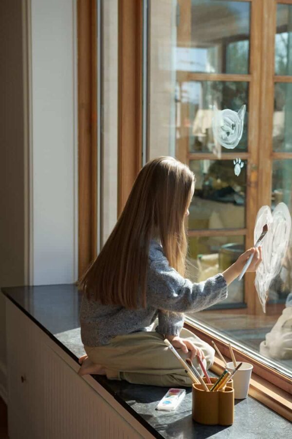 petite fille qui dessine avec un pot à crayons caramel en forme d'ours